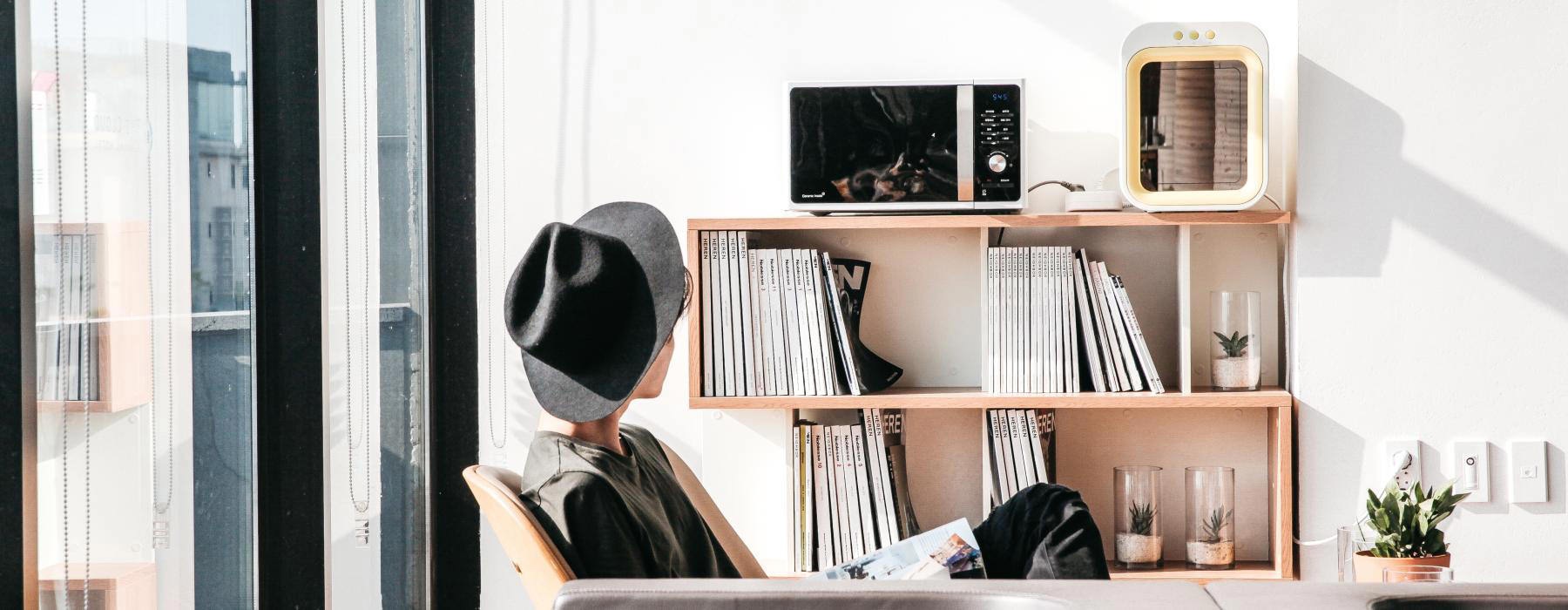 Lifestyle photo of a woman sitting in a sun filled room in front of bookshelves